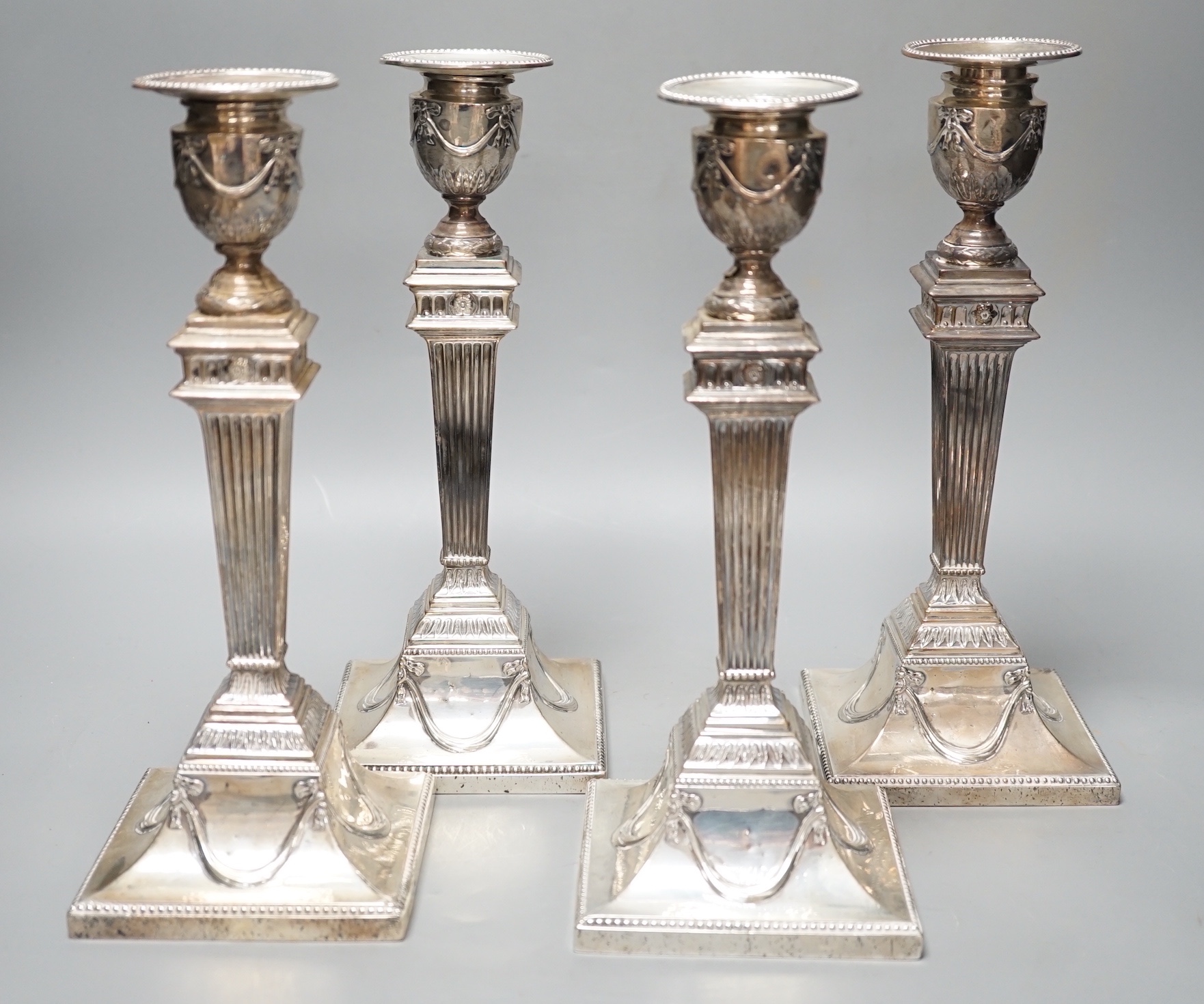 A set of four late Victorian silver candlesticks, with fluted, tapered stems, Hawksworth, Eyre & Co, Sheffield, 1890, 27.5cm, weighted (a.f.).